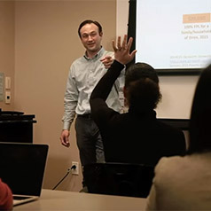 professor justin blackburn calling on student with raised hand in classroom